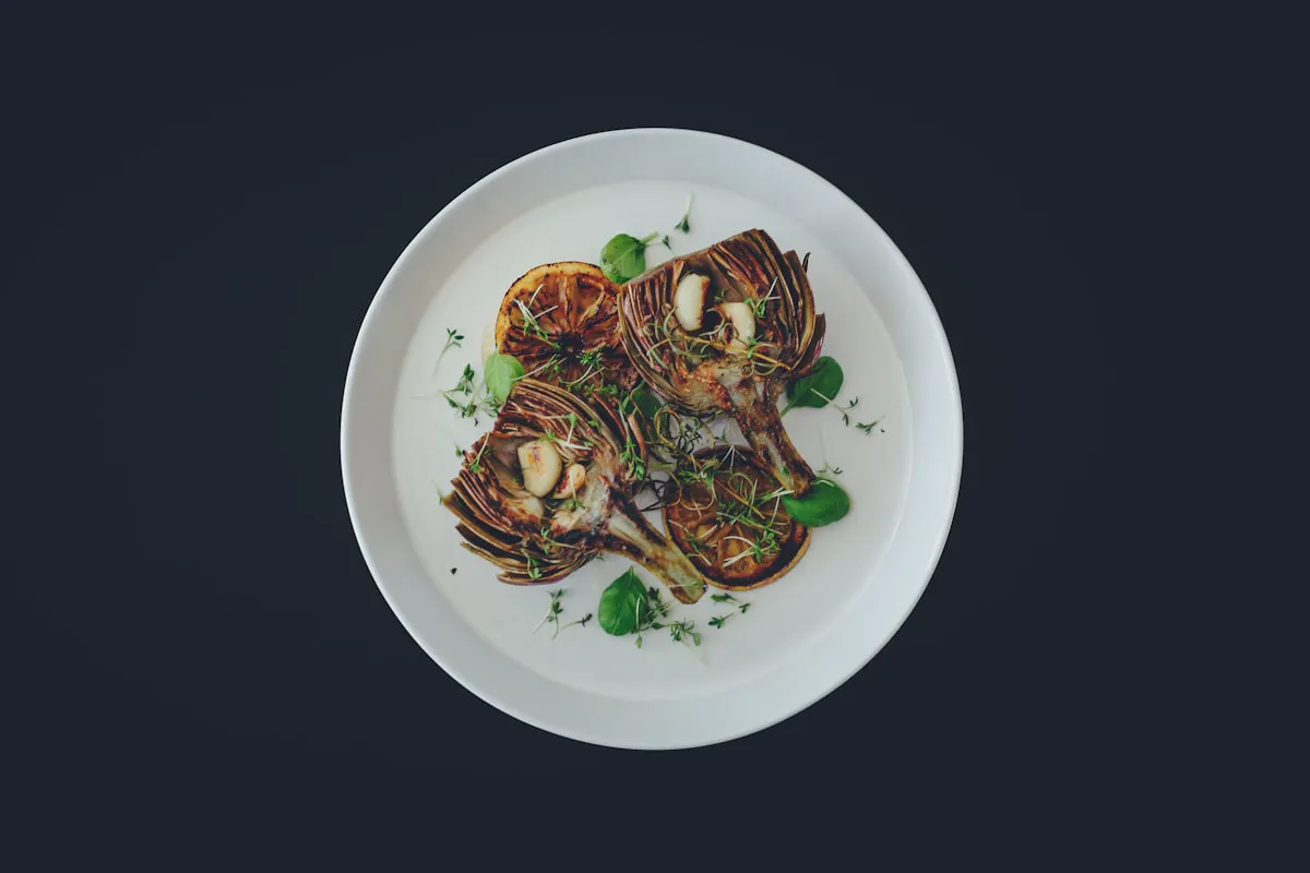 Grilled king oyster plated on white against a dark table